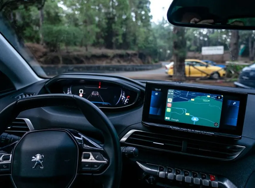 Une Peugeot 308 break d'occasion stationnée, hayon ouvert sur un coffre chargé, en extérieur.